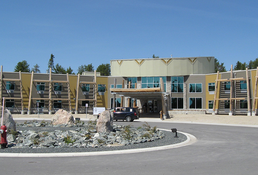 Wide, two-storey building with leaning wooden posts and a central entrance with a hand-drum inspired shape.